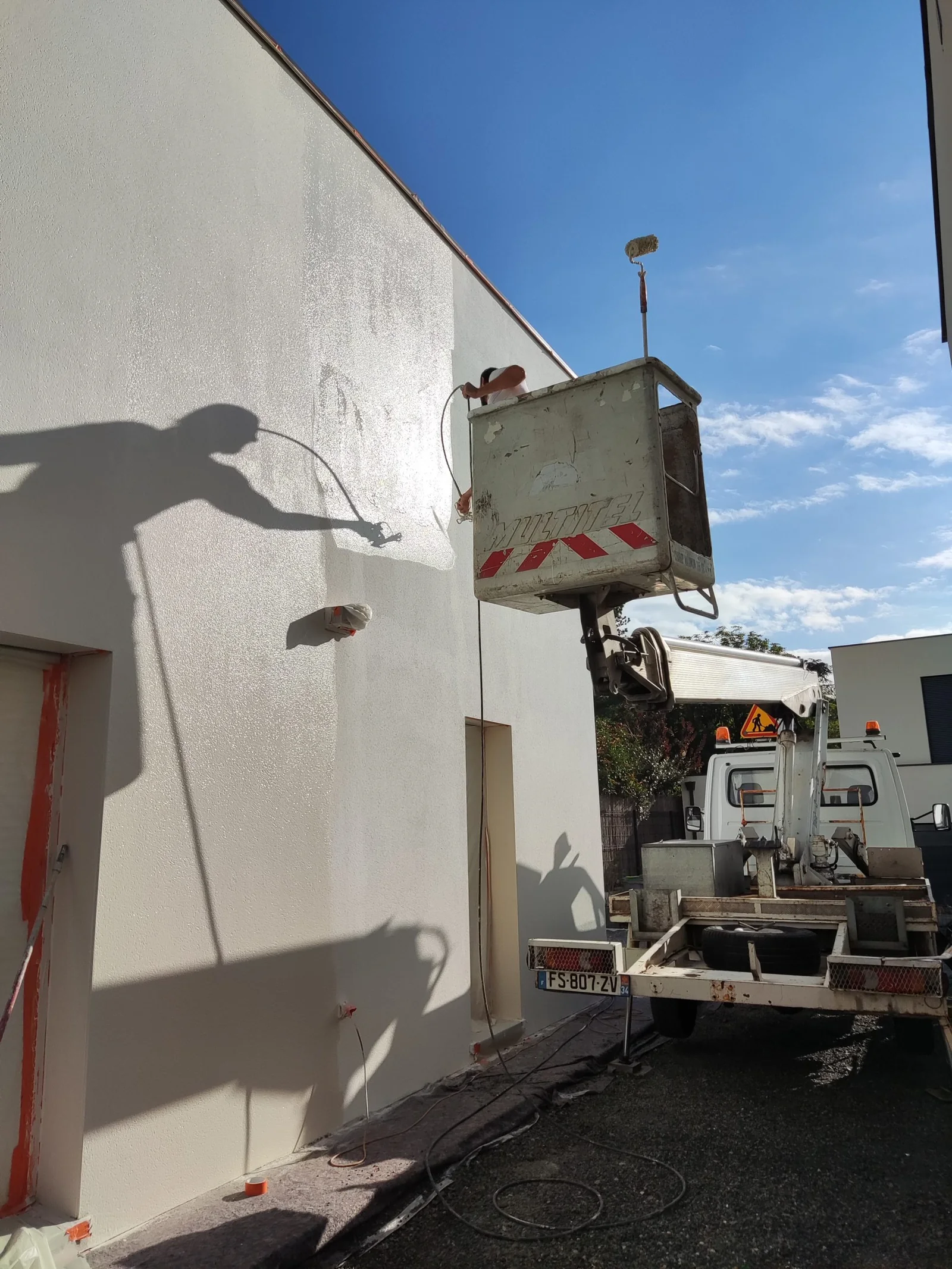 Artisan peintre en nacelle sur un chantier de façade
